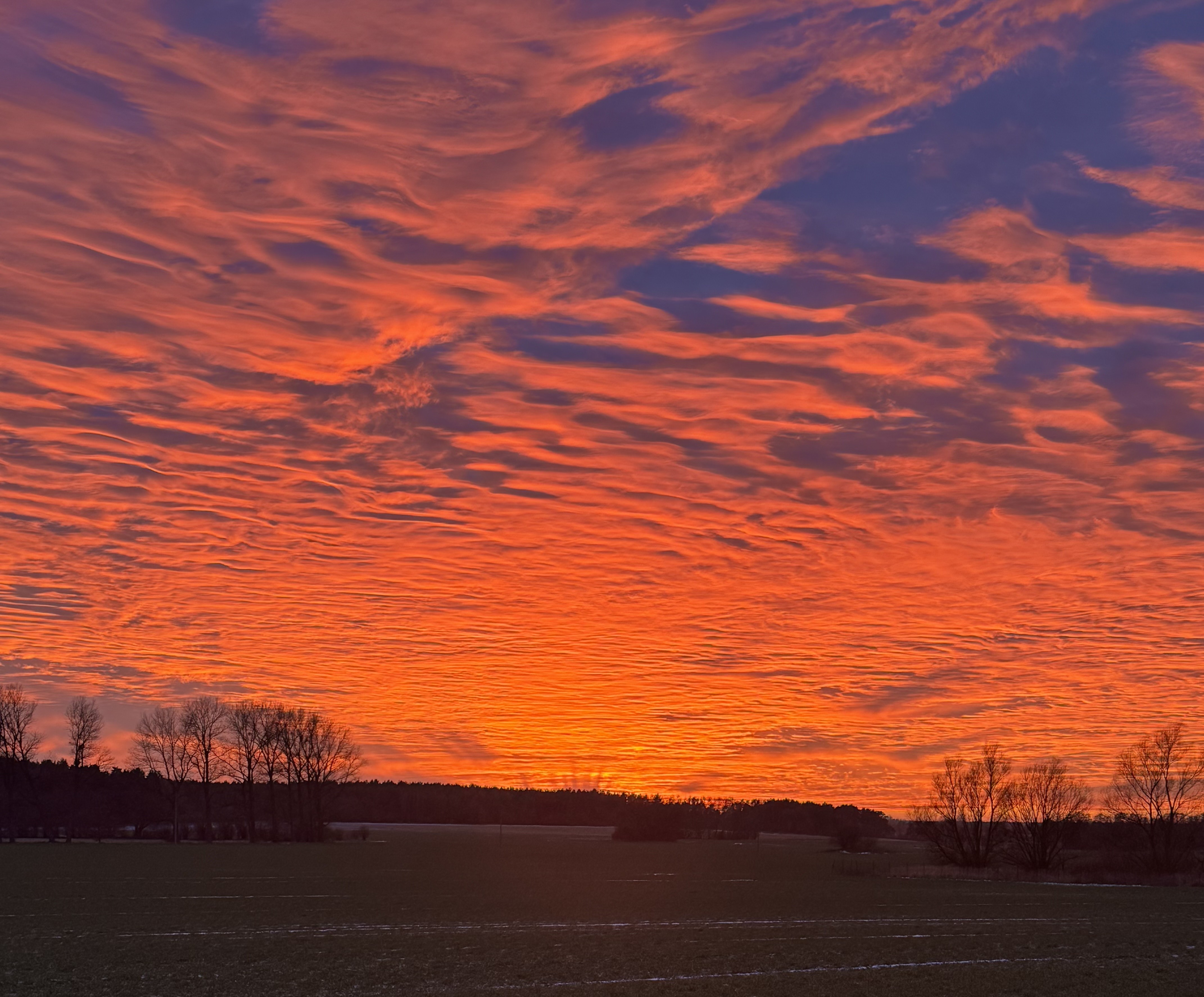 Atemberaubender Sonnenuntergang mit orangefarbenen und rosa Tönen über dem ländlichen Horizont